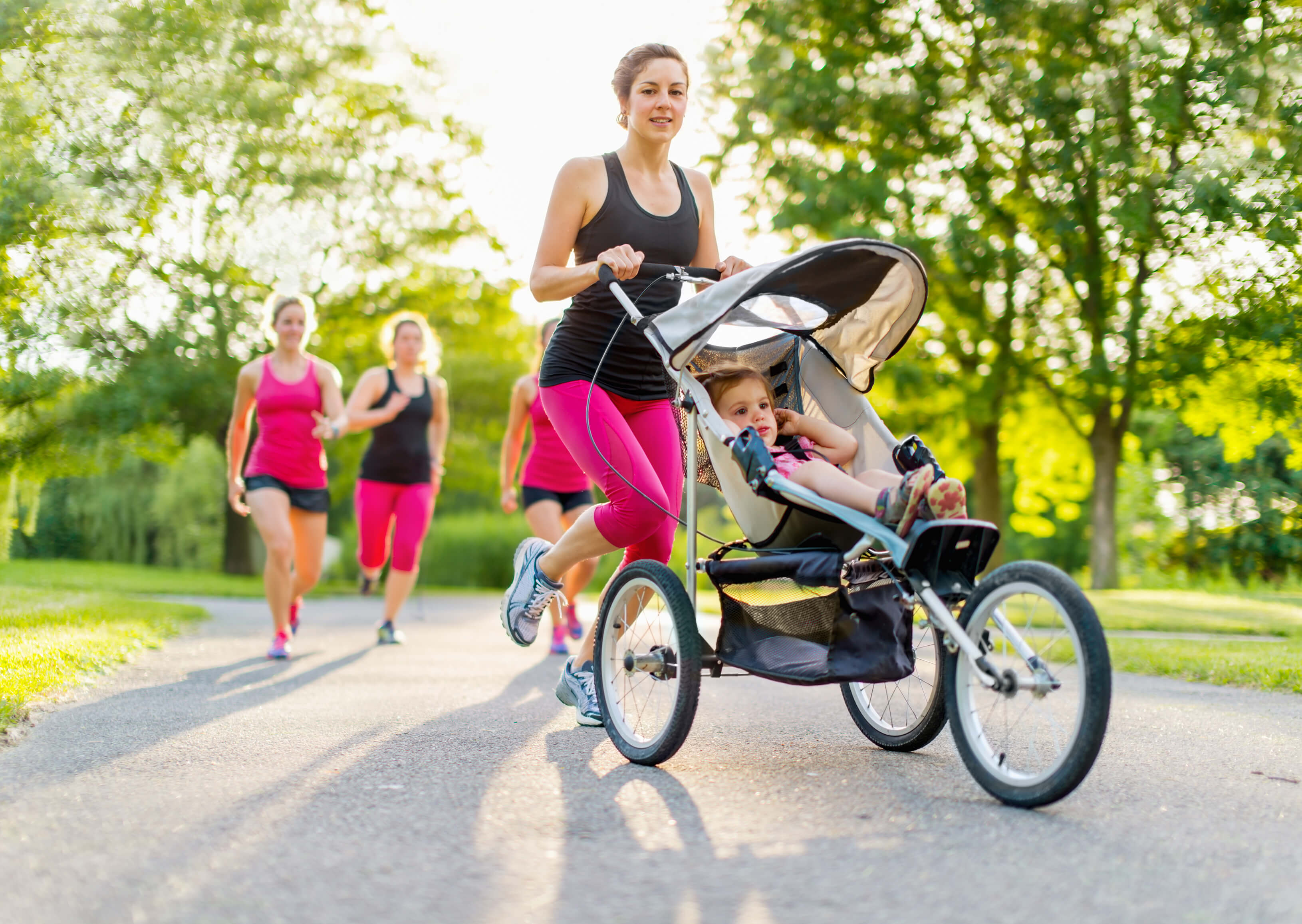 Frau joggt mit Sportkinderwagen indem ein Baby sitzt