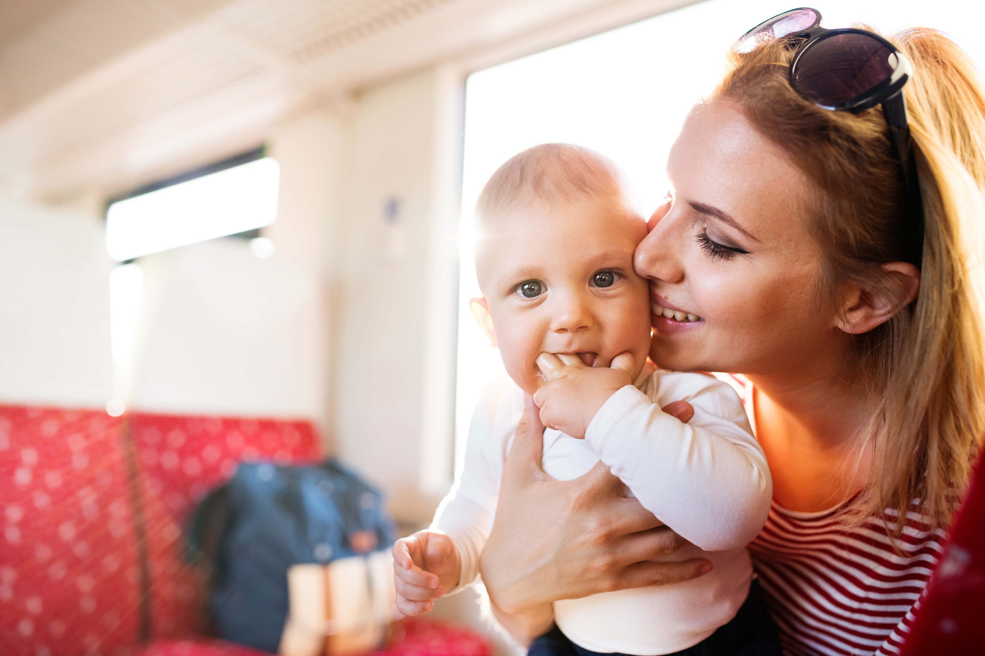 Lächelnde Mutter mit Baby im Zug bzw. in der Bahn