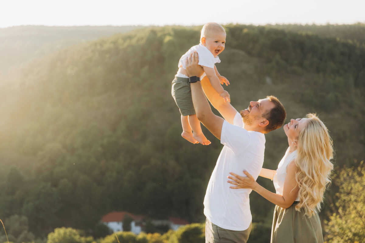 Fröhliches Baby mit Vater und Mutter in der Natur: Entwicklungskalender